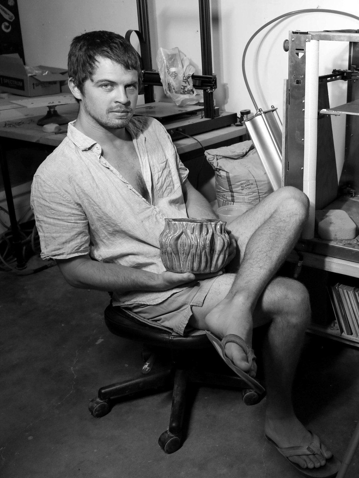 Orion Hansen seated in his studio holding a glazed vessel
